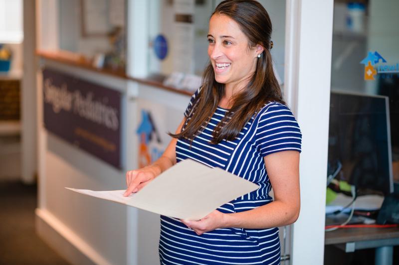 a pregnant medical provider holding a folder